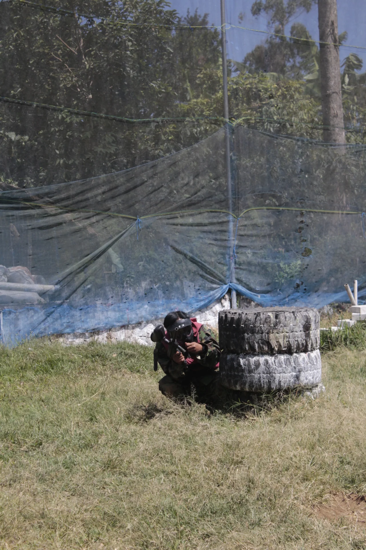 Peserta berlindung di balik ban saat bermain paintball di Pangalengan